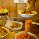 Assiettes de nouilles factices dans une vitrine de restaurant et à droit un des 6 millions de distributeurs japonais