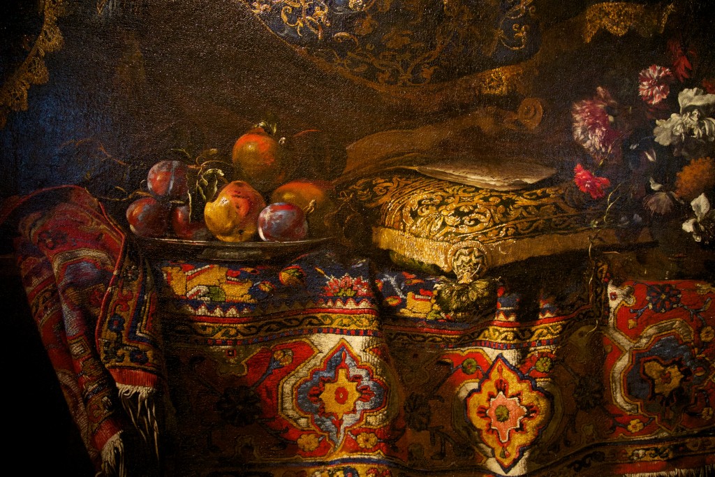 La douceur du tapis de la toile "Nature morte aux fruits et au tapis" de Noletti est presque à porté de main, n'est-ce pas ?