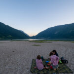Pique-nique sur la plage du lac de Santa Croce entouré des montagnes du nord de l'Italie